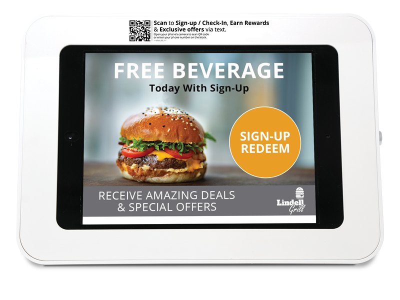 A kiosk photographed on a counter, its screen showing a free beverage sign-up offer